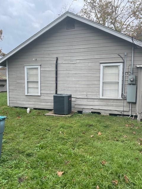 view of side of home with central air condition unit and a yard