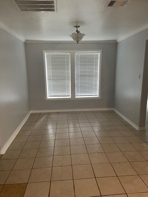 tiled spare room featuring crown molding