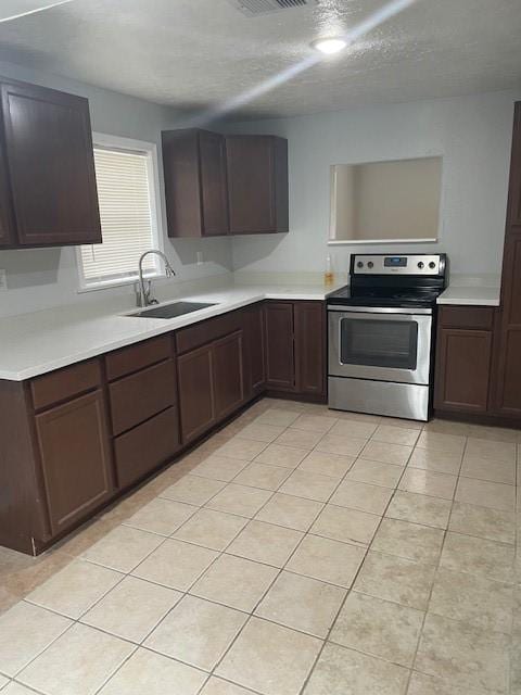 kitchen with a textured ceiling, electric stove, sink, and light tile patterned floors