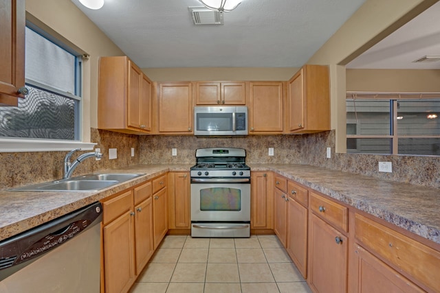 kitchen featuring appliances with stainless steel finishes, backsplash, light brown cabinetry, sink, and light tile patterned floors