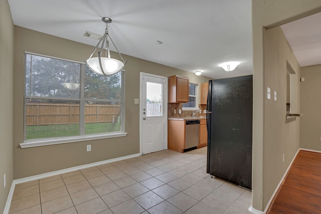 kitchen with decorative backsplash, black refrigerator, light tile patterned floors, decorative light fixtures, and dishwasher