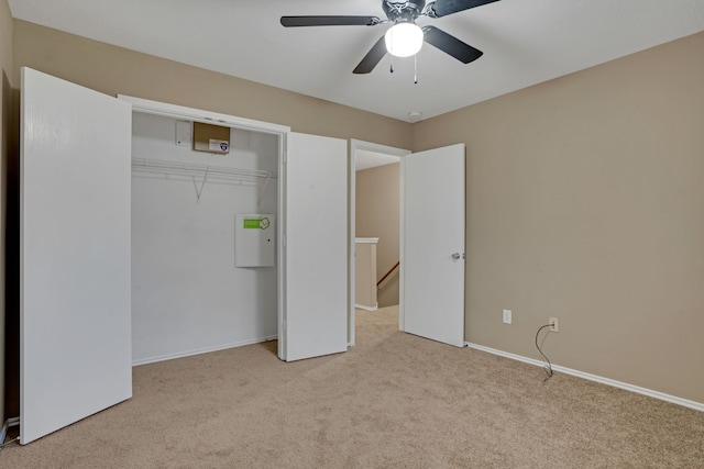 unfurnished bedroom featuring a closet, light colored carpet, and ceiling fan