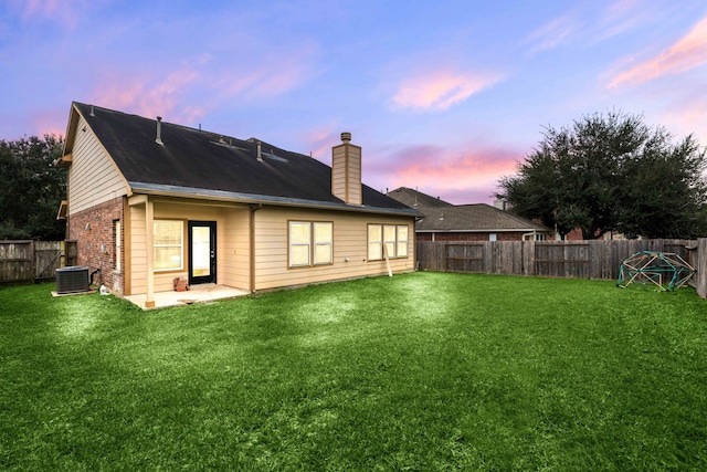 back house at dusk with a yard and a patio