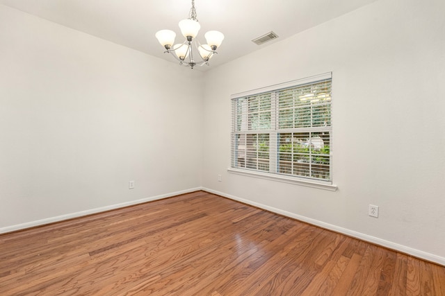 unfurnished room with hardwood / wood-style flooring and an inviting chandelier