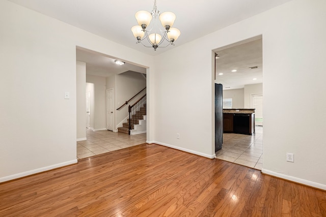 empty room with light hardwood / wood-style floors and a notable chandelier