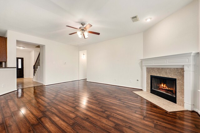 unfurnished living room with a premium fireplace, ceiling fan, and dark wood-type flooring