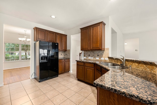 kitchen featuring black fridge with ice dispenser, light tile patterned flooring, a chandelier, and sink