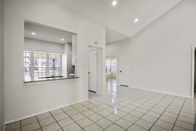 unfurnished room featuring a textured ceiling, light tile patterned floors, and lofted ceiling