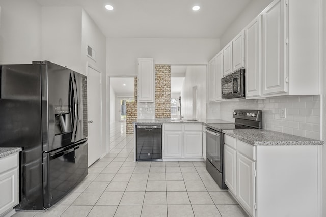 kitchen with black appliances, decorative backsplash, light tile patterned flooring, and white cabinetry