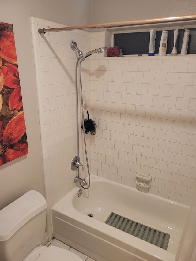 bathroom featuring tile patterned flooring, toilet, and tiled shower / bath