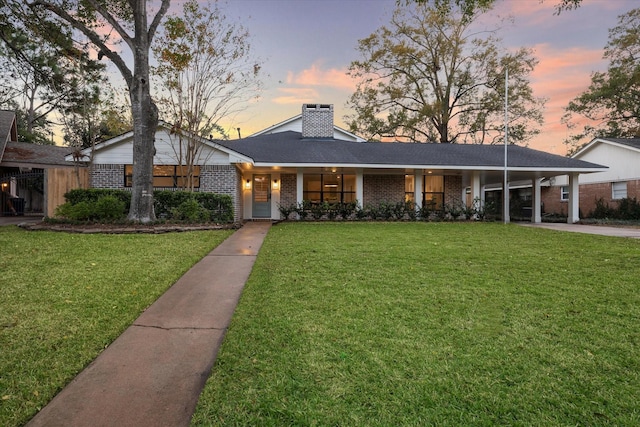 ranch-style house featuring a lawn and a carport