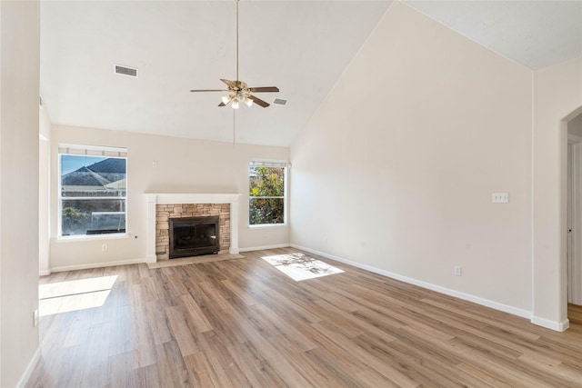 unfurnished living room featuring a fireplace, light hardwood / wood-style floors, high vaulted ceiling, and ceiling fan