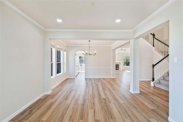 unfurnished living room with ornamental molding, light hardwood / wood-style flooring, ceiling fan, and a stone fireplace