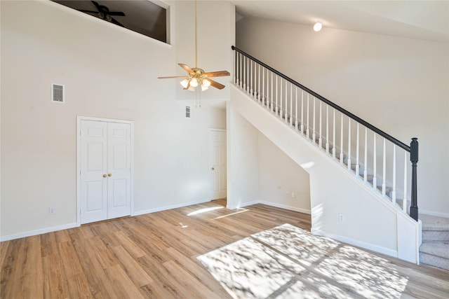 unfurnished living room featuring light wood-type flooring, high vaulted ceiling, and ceiling fan