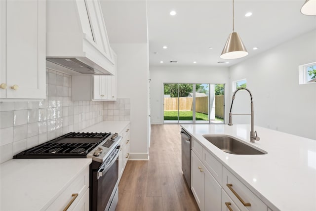 kitchen with appliances with stainless steel finishes, white cabinetry, hanging light fixtures, and custom exhaust hood