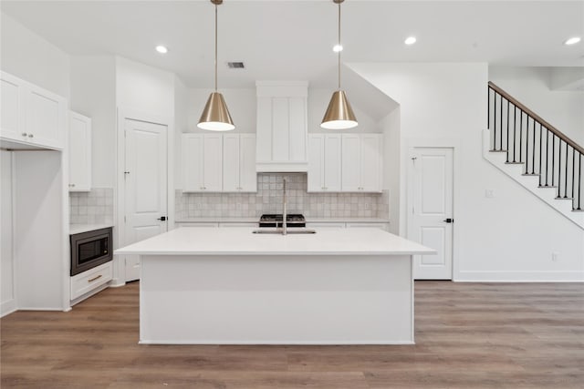 kitchen with an island with sink, white cabinets, and light hardwood / wood-style floors