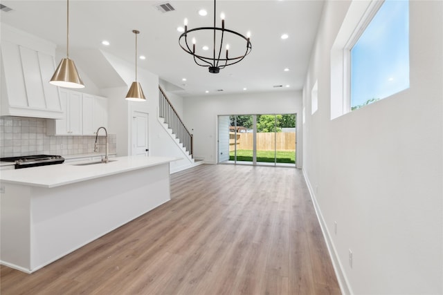 kitchen with tasteful backsplash, sink, pendant lighting, light hardwood / wood-style floors, and white cabinetry