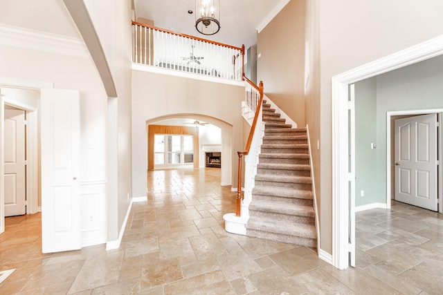 foyer featuring arched walkways, a high ceiling, baseboards, and stone tile floors