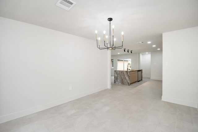 unfurnished room with an inviting chandelier and sink