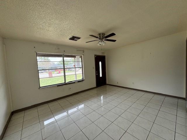 spare room featuring light tile patterned floors, a textured ceiling, and ceiling fan