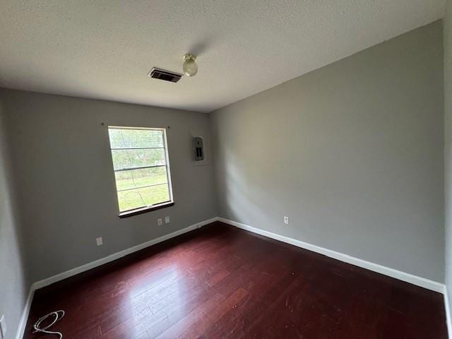 empty room with dark hardwood / wood-style flooring and a textured ceiling