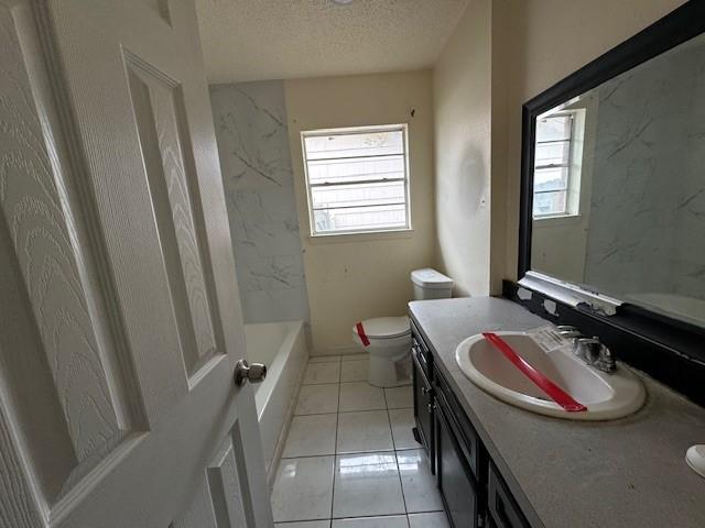 bathroom with tile patterned floors, vanity, a textured ceiling, and toilet