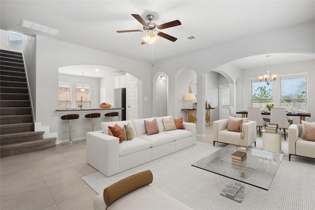 living room with sink, light tile patterned flooring, and ceiling fan with notable chandelier