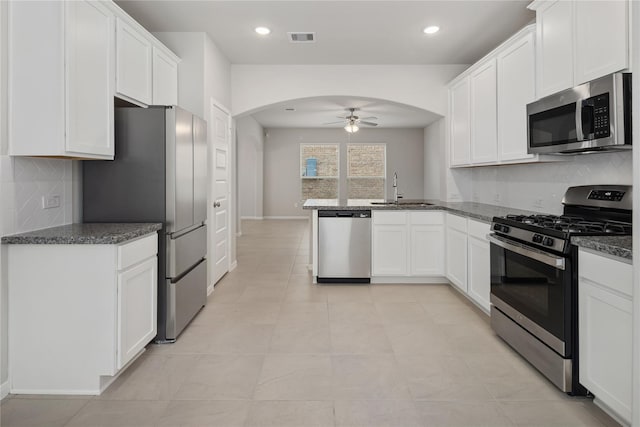 kitchen with kitchen peninsula, appliances with stainless steel finishes, white cabinetry, and ceiling fan