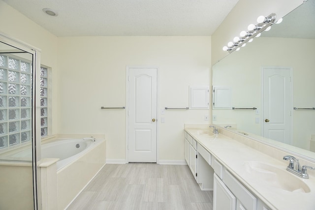 bathroom with a washtub, a textured ceiling, and vanity