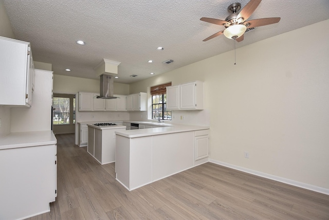 kitchen featuring island range hood, white cabinets, light hardwood / wood-style floors, and a kitchen island