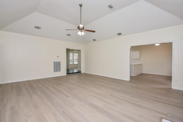 unfurnished room featuring a textured ceiling, light wood-type flooring, vaulted ceiling, and ceiling fan