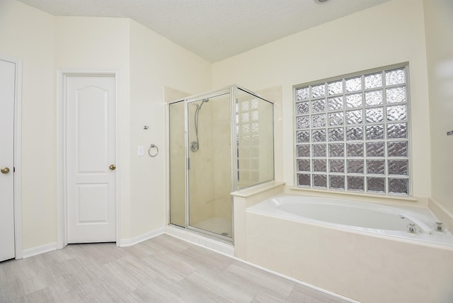 bathroom with hardwood / wood-style floors, separate shower and tub, and a textured ceiling