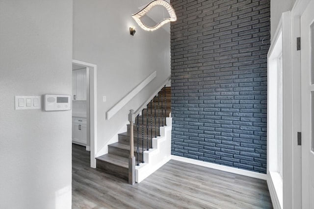 staircase featuring wood-type flooring and brick wall