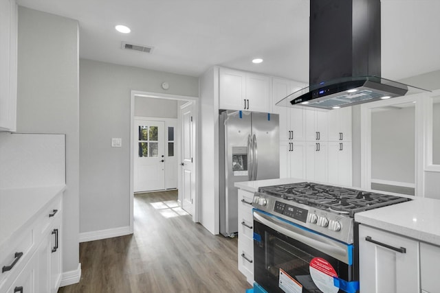 kitchen with white cabinets, light hardwood / wood-style flooring, island range hood, light stone counters, and stainless steel appliances