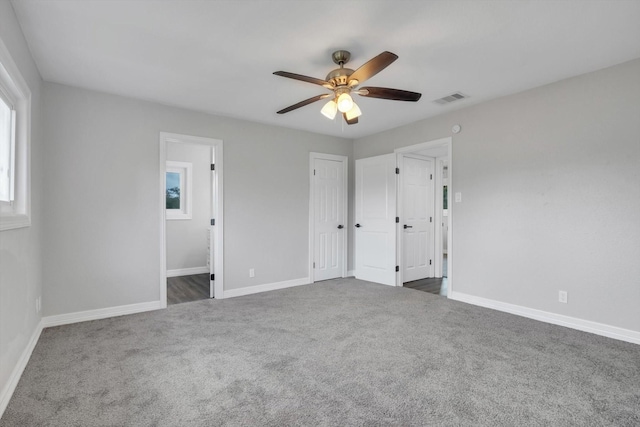 unfurnished bedroom with dark colored carpet, ceiling fan, and ensuite bathroom