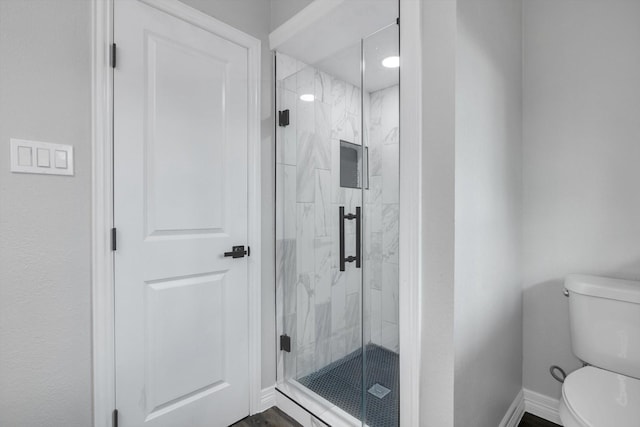 bathroom featuring toilet and a shower with door