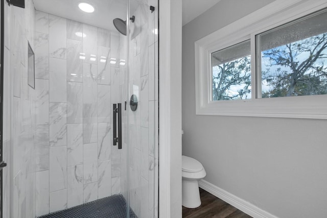 bathroom with hardwood / wood-style floors, toilet, and an enclosed shower