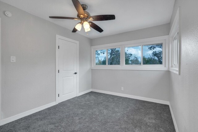 unfurnished room with dark carpet and ceiling fan