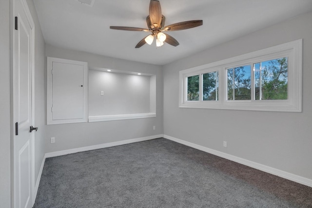 unfurnished room with ceiling fan and dark carpet