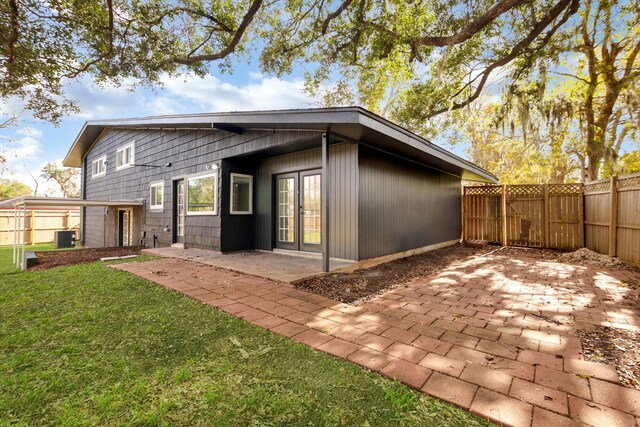 rear view of property featuring french doors, cooling unit, a patio area, and a lawn