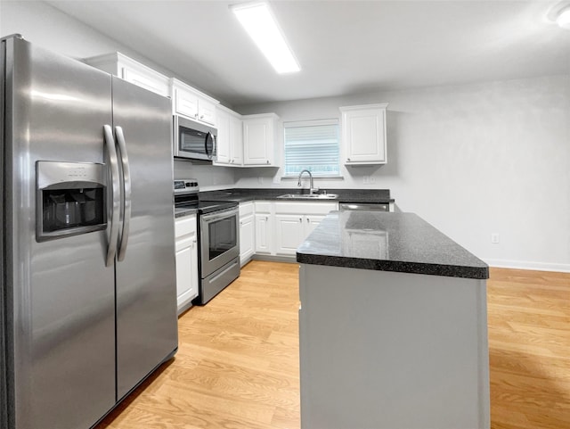 kitchen with stainless steel appliances, sink, light hardwood / wood-style flooring, a center island, and white cabinetry