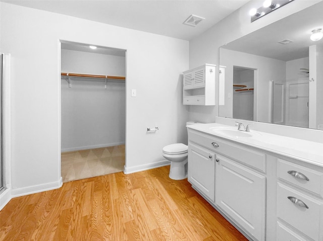 bathroom featuring an enclosed shower, vanity, toilet, and wood-type flooring