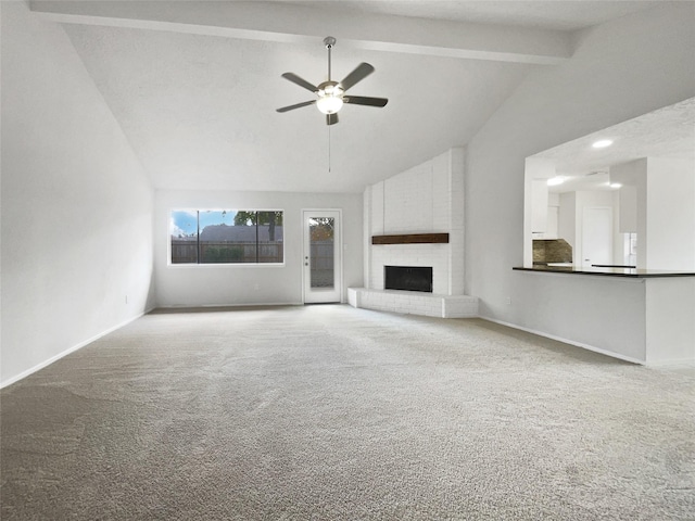 unfurnished living room featuring carpet flooring, lofted ceiling with beams, a brick fireplace, and ceiling fan