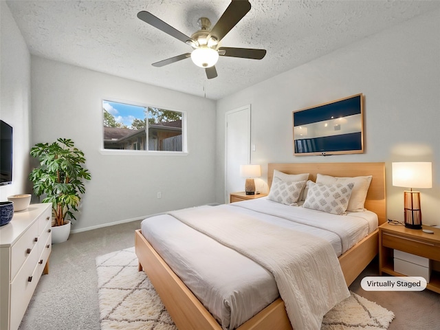 bedroom featuring ceiling fan, light colored carpet, and a textured ceiling