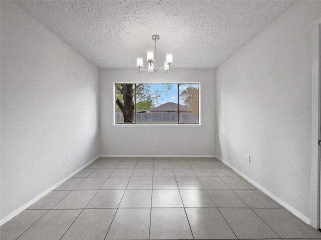 tiled empty room with a notable chandelier and a textured ceiling