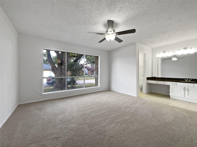 unfurnished bedroom featuring ceiling fan, light carpet, and a textured ceiling