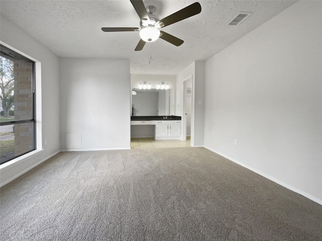 unfurnished living room featuring light carpet, ceiling fan, and a textured ceiling