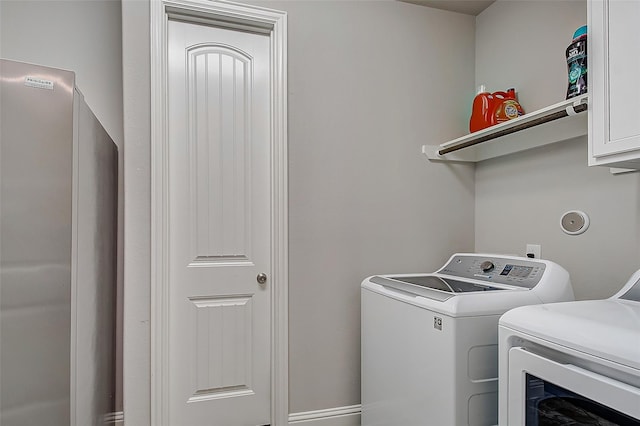 washroom with cabinets and washing machine and clothes dryer