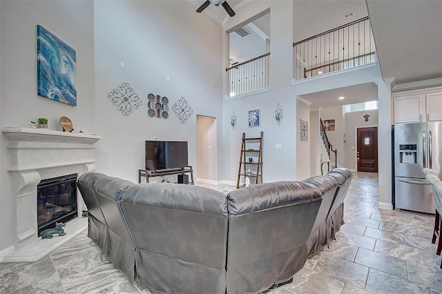 living room featuring a high ceiling, ceiling fan, and ornamental molding