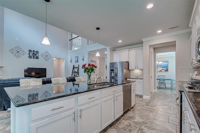 kitchen with white cabinetry, sink, stainless steel appliances, decorative light fixtures, and a kitchen island with sink